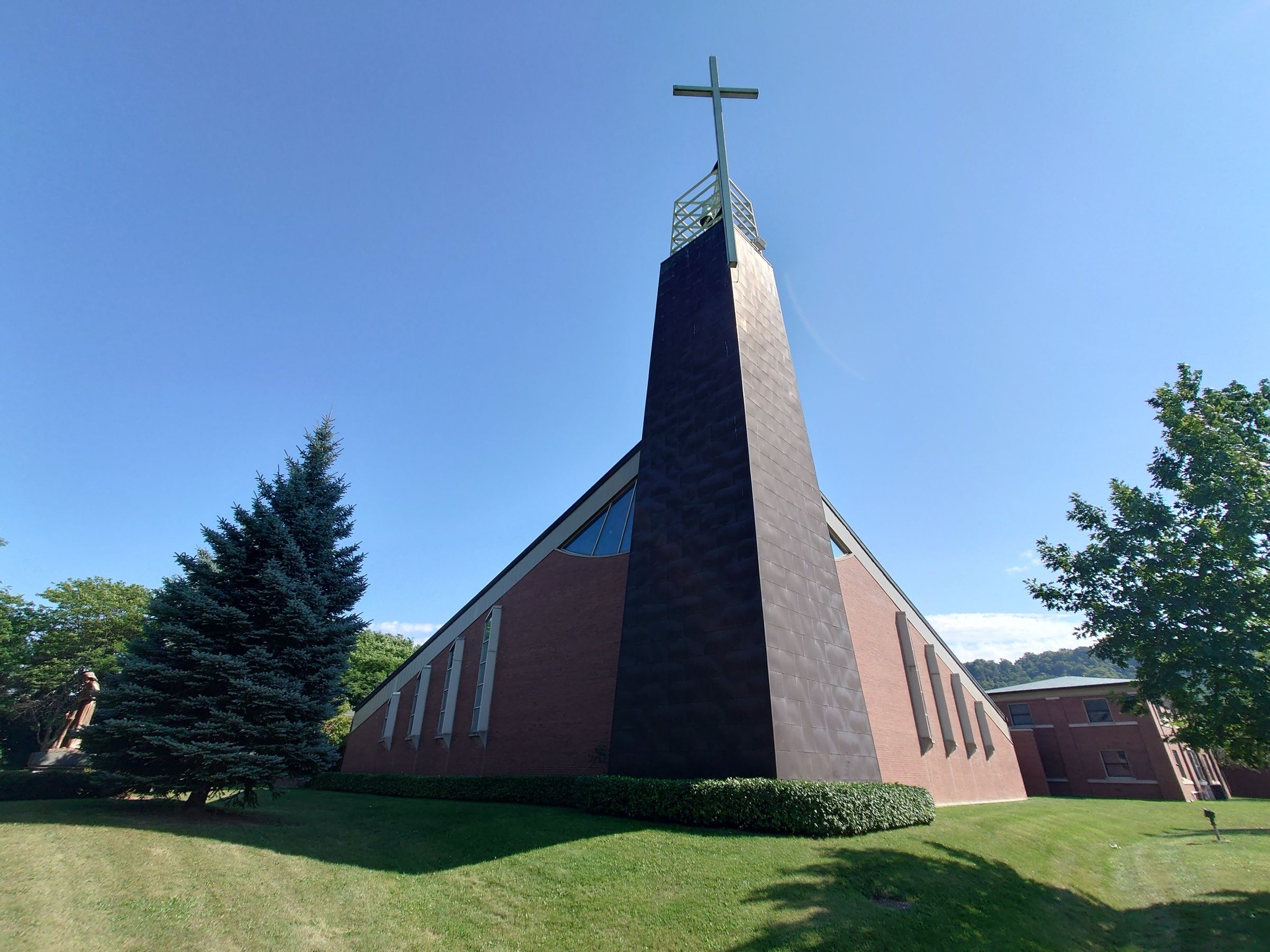 St. Joseph Catholic Church, a brick church whose tall metal-clad tower, topped by an open lattice and a cross, rises in front of its steep gable
